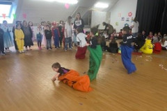 Kinder in Kostümen tanzen fröhlich in einer Turnhalle.