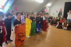 Kinder in Kostümen halten bunte Ballons und lächeln fröhlich in die Kamera.