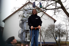 Ein Kind steht auf einer Leiter unter dem Futterhäuschen.