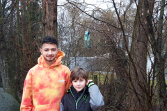 Ein Mann und ein Junge stehen lächelnd vor einem großen Baum.