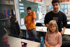 Kinder lernen in einem Klassenzimmer, während die Lehrerin ihnen aufmerksam zuschaut.