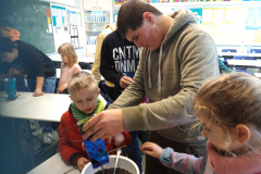 Ein Mann und zwei Kinder arbeiten gemeinsam an einem Projekt und zeigen dabei viel Freude und Teamgeist.