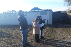 Drei Personen stehen lächelnd vor einem Schuppen.