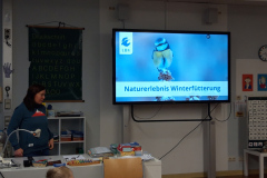 Ein Klassenzimmer mit einem Bildschirm, auf dem ein Vogel abgebildet ist.