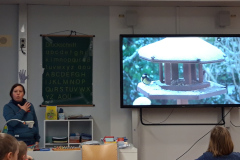 Eine Frau präsentiert vor einer Schulklasse, während die Schüler interessiert auf sie schauen.