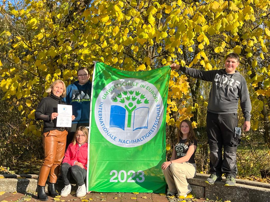 Umwelschule Abzeichen in die Luft halten.