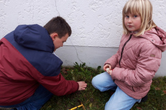 Zwei Kinder sammeln was am Boden.