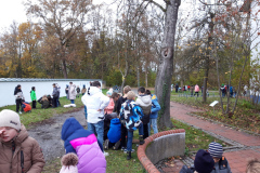 Kinder stehen neben einem Baum und hören aufmerksam zu.